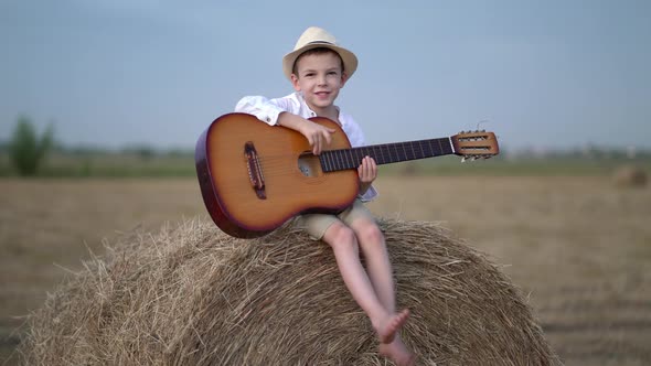 Little Boy on a Haystack with a Guitar