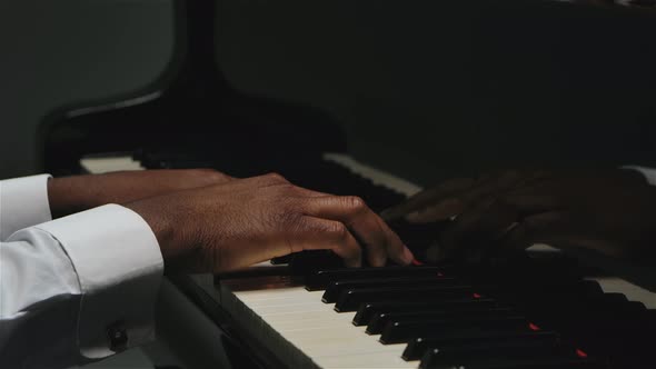 An African American Man with Two Hands Plays Gentle Classical Music on the Grand Piano. Close Up