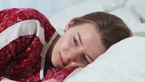 Closeup of a Blonde Girl Waking Up in Her Lightcolored Bed