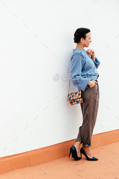 ater with heels and standing with clutch bag outdoors
