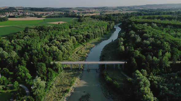 A biker crossing a beautiful river on a small bridge