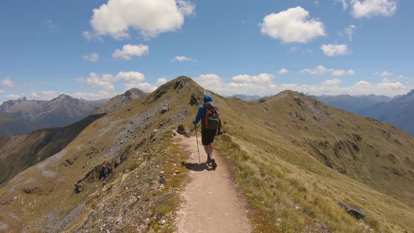 Follow, hiker crosses exposed alpine ridge, vast mountain landscape, Fiordland, Kepler Track New Zea