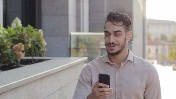Hispanic Business Man Smiling Walking City Street Looking at Mobile Phone Online Map Application App