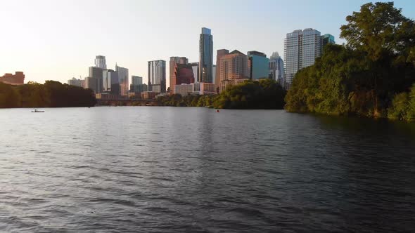 Low drone shot of a Kayaker paddling towards Downtown Austin Texas. Shot August 2020