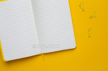 Notebook with blank pages and paperclip light bulb idea on yellow background