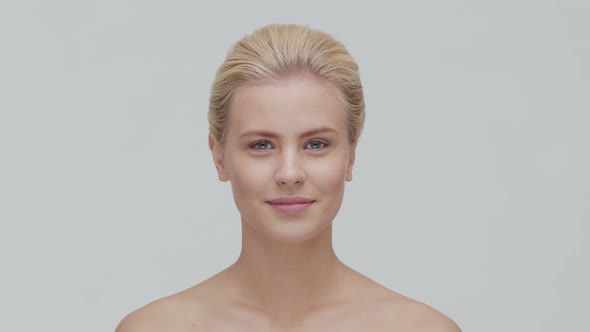 Studio portrait of young, beautiful and natural blond woman applying skin care cream. F