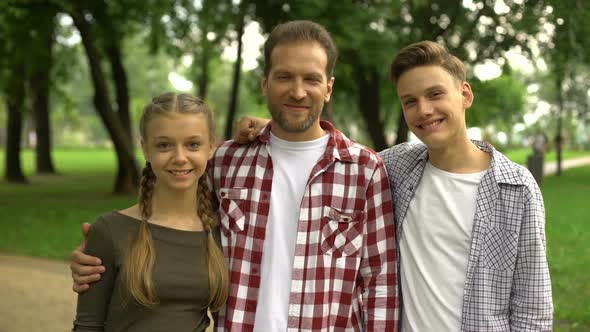 Joyful Teenagers and Their Father Showing Thumbs Up Into Camera at Park, Family