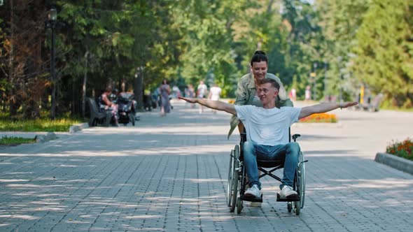 Friends Walking in Park  a Man in a Wheelchair and His Female Friend Fooling Around