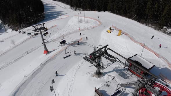 Aerial View of Ski Slopes with Skiers Go Down Under Ski Lifts on Ski Resort