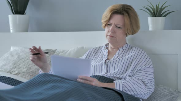 Old Senior Woman Signing Documents in Bed Paperwork