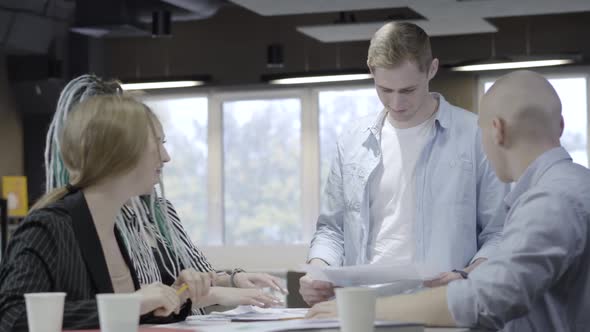 Group of Positive Young Caucasian Coworkers Talking and Laughing Sitting in Office