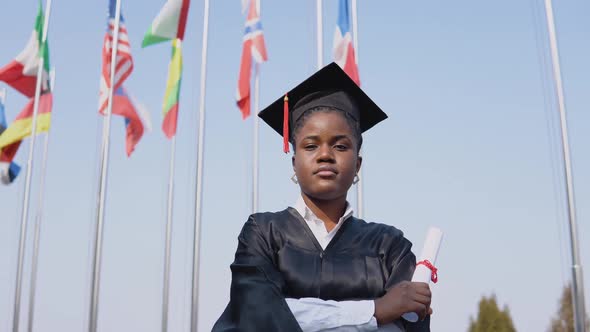 Young African American Female Graduate Standing in Front of the Camera with a Diploma in Her Hands