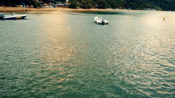 Boats waiting close to the shore. A cloudy day on the beach with very calm water. A good vacation al