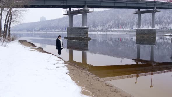 Beautiful Woman With Sad Emotion Walks On River Bank Thinking. Winter Snow