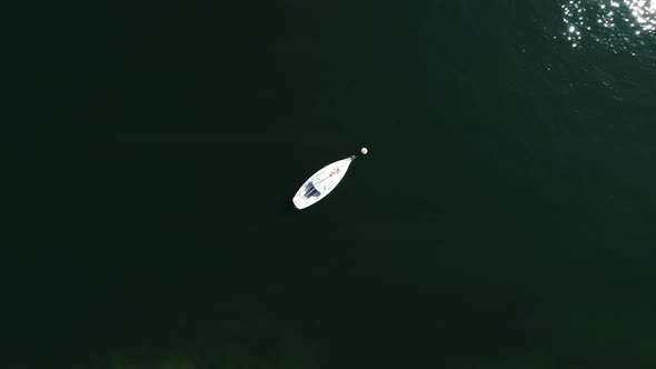 aerial shot top down of little sailing boat in a lake, flying up switzerland