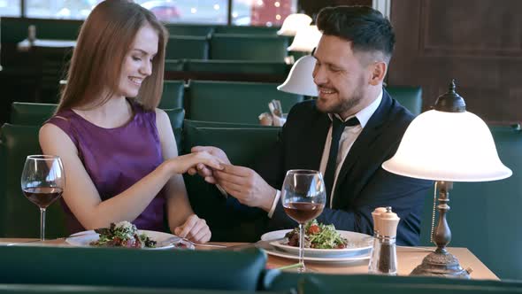 Man Putting Ring on Finger of Woman on Date