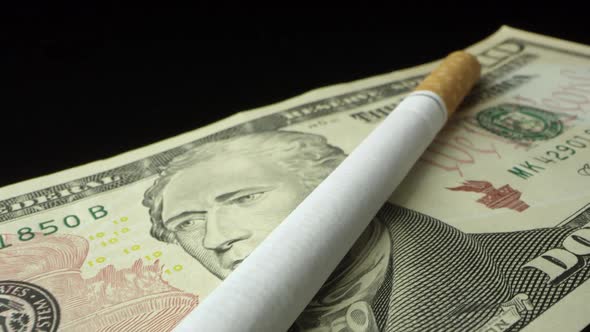 Panning over cigarette on top of ten dollar bill