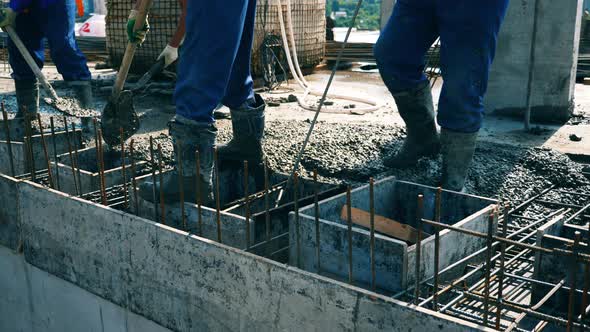 Builders Level Cement on a Floor While Working at a Construction Site.