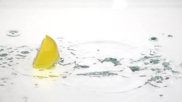 Half a Lemon Drops Into the Water. White Background. Slow Motion