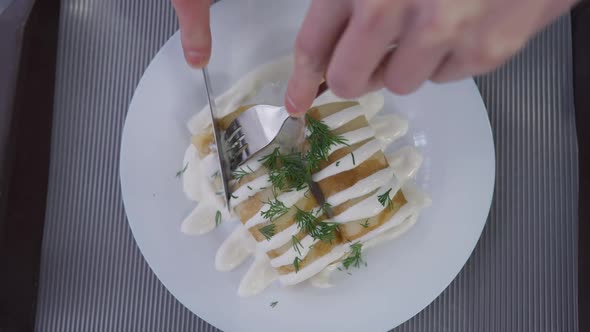 Top View Male Hands Cutting Stuffed Rolled Pancakes with Topping on Dinner Plate