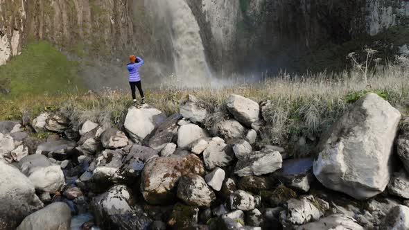 A Girl Is a Professional Landscape Photographer Standing on a Stone By the River and Photographing a