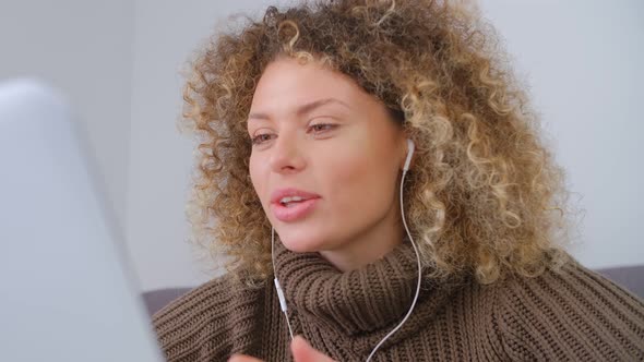 Cheerful curly woman in headset talking on laptop web camera with toothy smile in 4k video