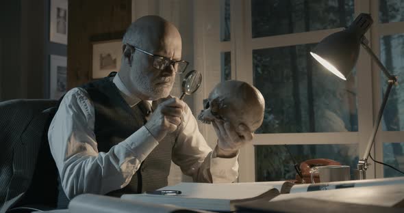 Professor sitting at desk and checking a human skull