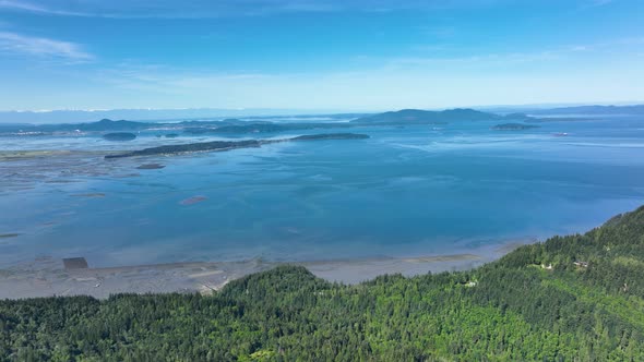 Drone shot of Samish Bay with islands in the distance and lush forests along the coast.