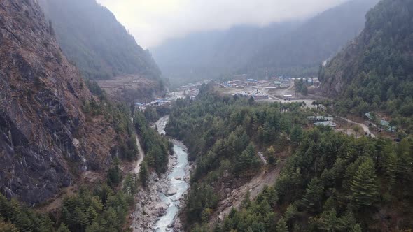 Aerial view following river through canyon to Chame Village in Nepal