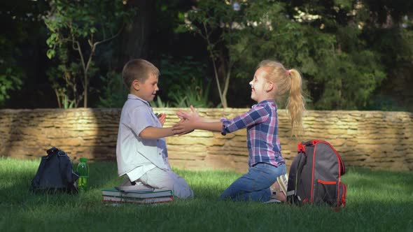 Educational Games, Scholar Girl and Boy Playing Clapping Game Sitting on Lawn After Schooling on