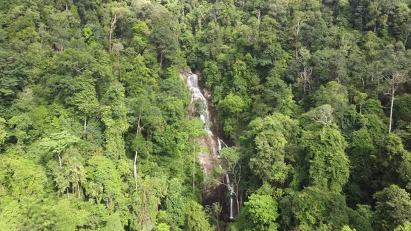 Aerial fly toward waterfall at green forest