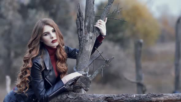 Portrait of Gorgeous Sexy Girl Young Woman with Long Hair Standing Near a Dry Tree and Looking at