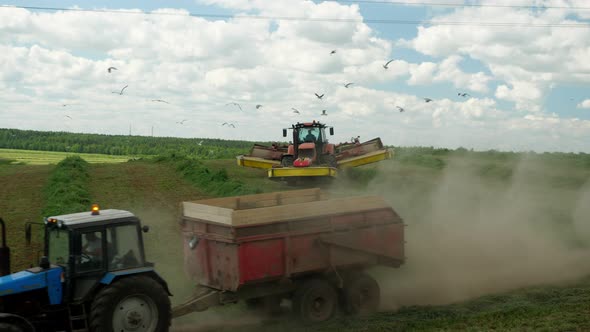 Two Tractors Work on the Field Removing the Grass a Lot of Dust Work Boils