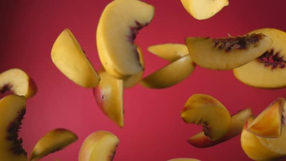 Slices of the Fresh Ripe Peach are Bouncing on the Wine Red Background