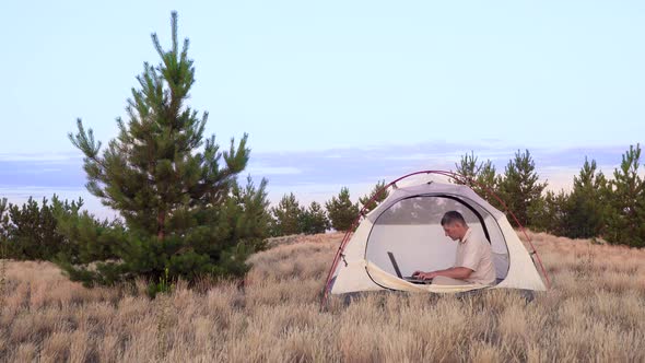 Businessman Works Behind a Laptopin in a Tent