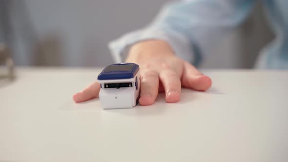 A Doctor in Latex Gloves Using a Pulse Oximeter Measures the Level of Oxygen in the Patient's Blood