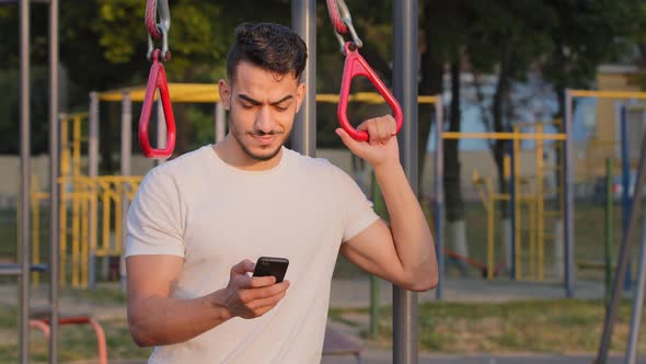 Middle Eastern Arab Millennial Athlete Using Sports Equipment at City Stadium Received Text Message