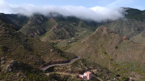 Massive clouds roll over hilltops in Tenerife island, aerial view of majestic valley