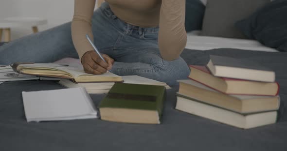 Black Female Student Studying with Books in Bed