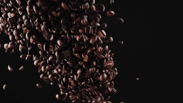 Black Coffee Beans Fly Up From the Bottom on a Black Background