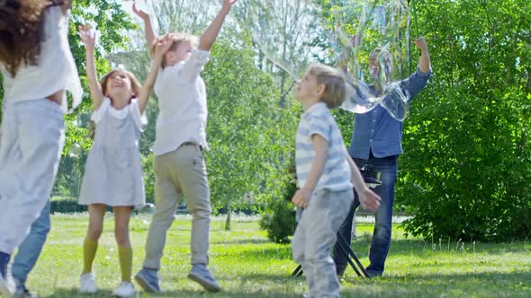 Man Making Giant Bubbles for Kids in Park