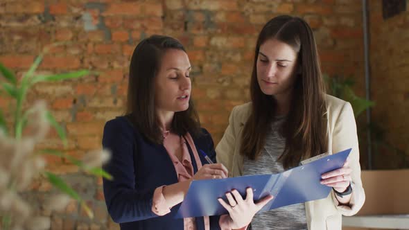 Caucasian female business owner and her coworker having business talk and making notes