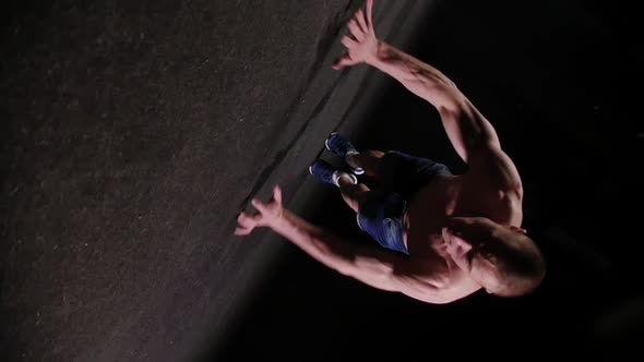 A Handsome Young Sports Man Doing Hard Push Ups in Black Studio