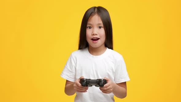 Asian Girl Playing Video Game Having Fun Over Yellow Background