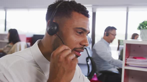 Professional businessman smiling while talking on phone headset in modern office in slow motion