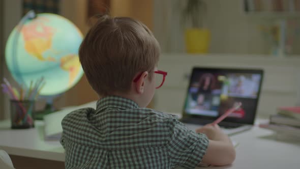 Preschool Boy Having Online School Lesson with Group of Teacher and Pupils on Laptop Screen