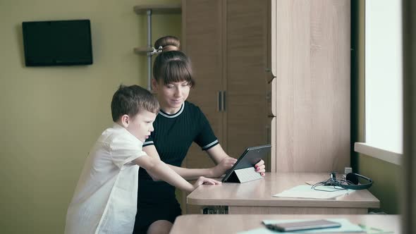 Mother Helps Her Son Do Homework for School Uses a Tablet Computer