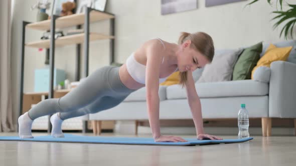 Tired Young Woman Trying to Do Pushups on Yoga Mat at Home