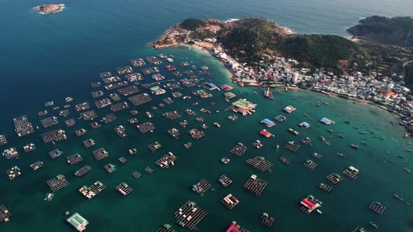 Aerial, floating fish farms on tropical ocean island coast in Southeast Asia