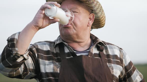 Senior Worker in Apron Holding Drinking Beer at Field